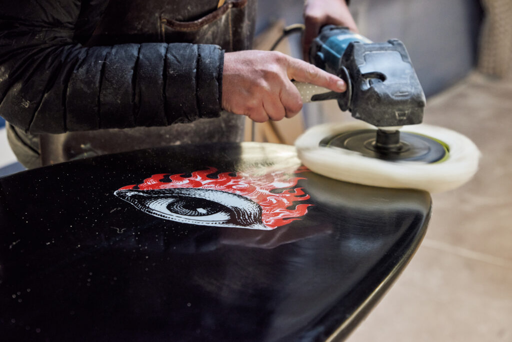 Gloss polish being applied and buffed on the bottom deck of a surfboard at Melbourne Surfboard Repairs.