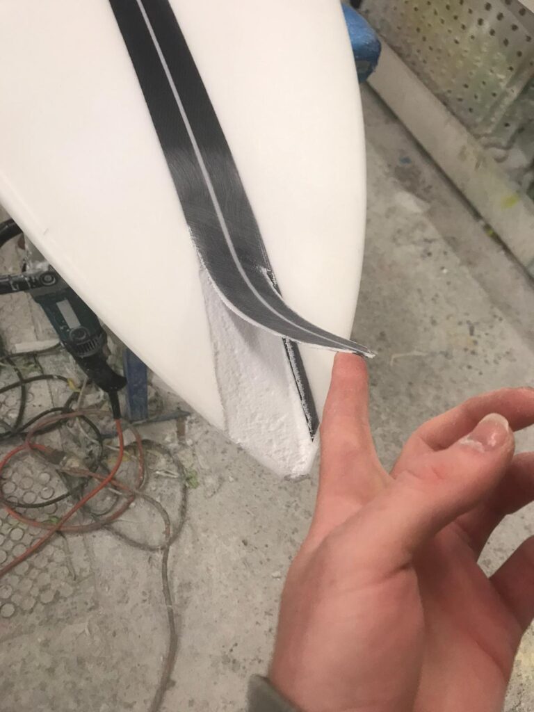 A Surfboard with the fibreglass delamination on the nose needing to be repaired